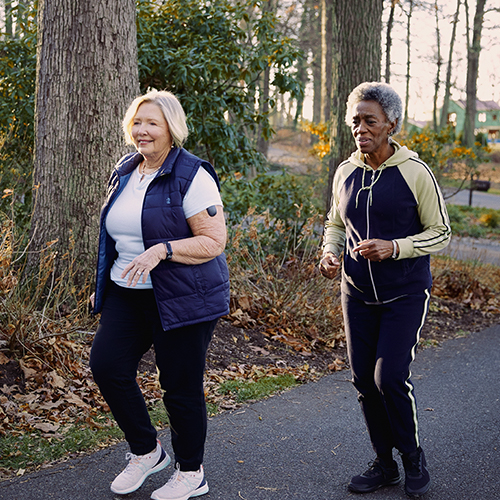 Dos mujeres con dispositivos de MCG Eversense caminando al aire libre.